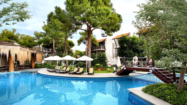 A pool area with lounge chairs, umbrellas, and a staircase leading to a building.
