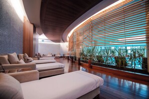 A spa area with massage chairs, a wooden ceiling, and a view of a pool through large windows. - Gloria Golf Resort - All Inclusive (Serik)