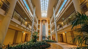 A hotel atrium with a central elevator, multiple floors, and a central garden area. - Gloria Golf Resort - All Inclusive (Serik)