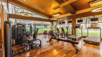 Une salle de sport équipée de matériel d’exercice, dotée de grandes fenêtres et d’un plancher en bois.