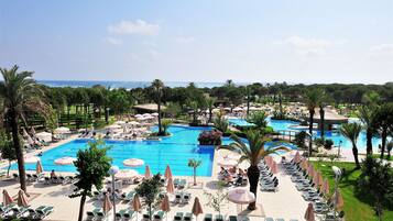 Relax by the resort's inviting pool surrounded by lush greenery and palm trees.