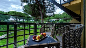 A balcony with wicker furniture and a tray of fruit.