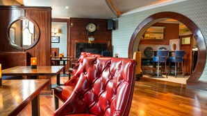 A restaurant with wooden furniture, a red leather chair, and a clock on the wall. - Benners Hotel (Tralee)