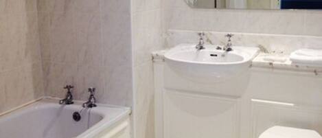 A bathroom with a bathtub, two sinks, a toilet, and a mirror.
