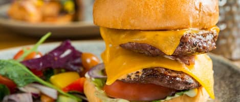 A close-up of a burger with a bun, cheese, and a beef patty, accompanied by a side salad.