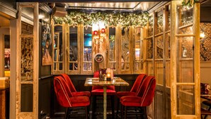 A cozy dining area with a table and red chairs, decorated with festive garlands and candles. - Benners Hotel (Tralee)