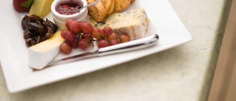 Un plato con quesos variados, frutas y nueces sobre una mesa.