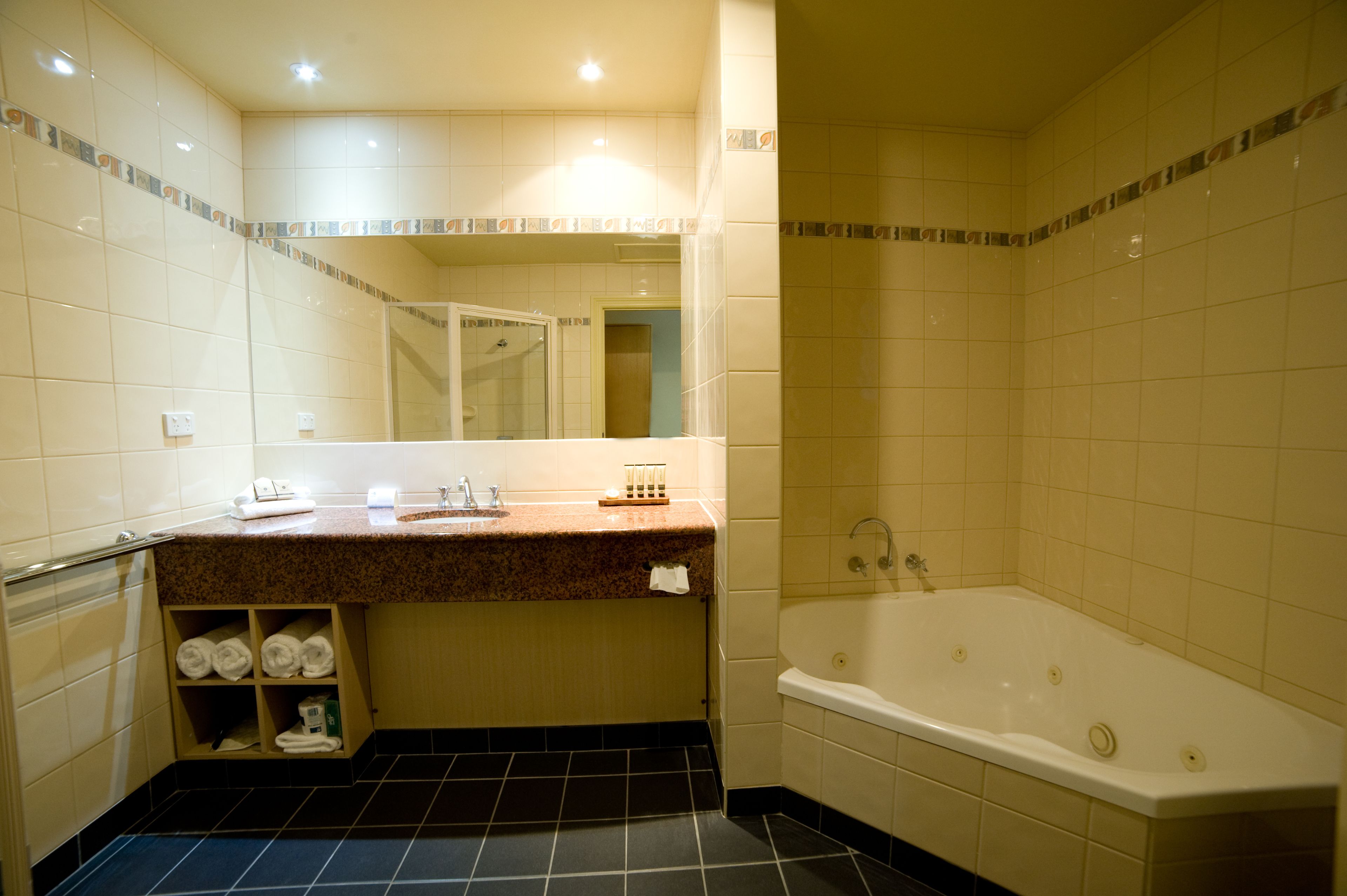Un baño con bañera, lavabo con espejo y estantes con toallas.