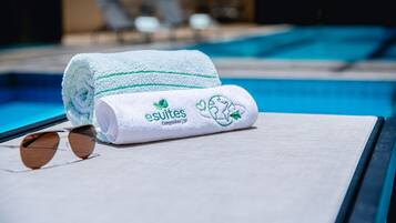 Et håndklæde med logo og tekst, solbriller og en poolside-scene.