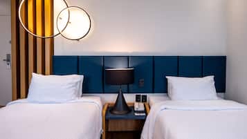 Une chambre d’hôtel avec deux lits, une tête de lit en bois, une table de chevet avec une lampe et un téléphone.