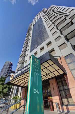 Un grand immeuble d’hôtel à la façade vitrée, une enseigne indiquant qu’il s’agit d’un « hôtel de qualité, membre du groupe Choice Hotel », et le numéro 247 sur une enseigne verte.