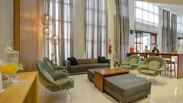 Un ampli vestíbul d'hotel amb un sofà, cadires, una taula de cafè i una vitrina de vidre.