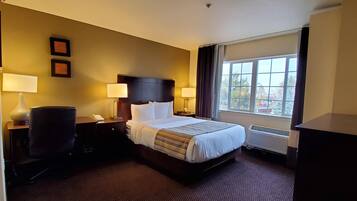 Hotelkamer met een bed, twee bedlampen, een stoel, een bureau met telefoon en een raam met uitzicht.