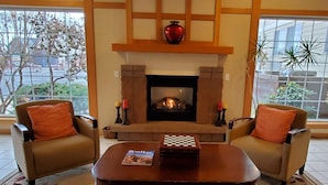 Una sala de estar con chimenea, dos sillones, una mesita de centro y una revista.