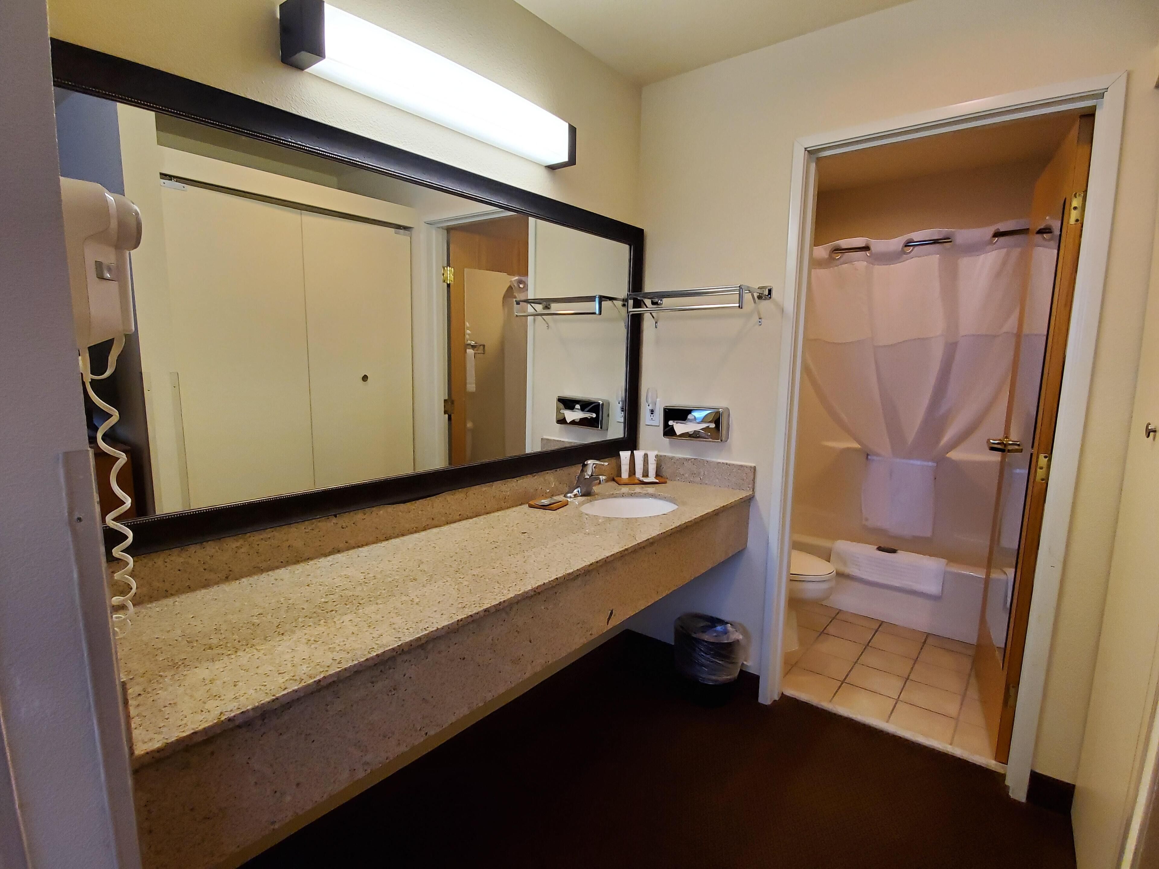 A bathroom with a sink, mirror, towel rack, and shower curtain.