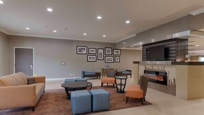 A modern living room with a sofa, ottomans, a coffee table, and a fireplace. - Best Western Plus Delta Inn & Suites (Oakley)
