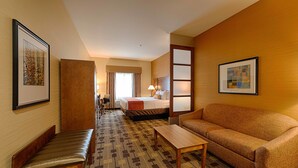 A hotel room with a bed, a sofa, a desk, a bench, and a framed picture on the wall. - Best Western Plus Delta Inn & Suites (Oakley)