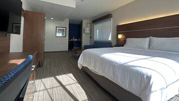 Een hotelkamer met een groot bed, een bureau, een stoel, een televisie en een raam met gordijnen.