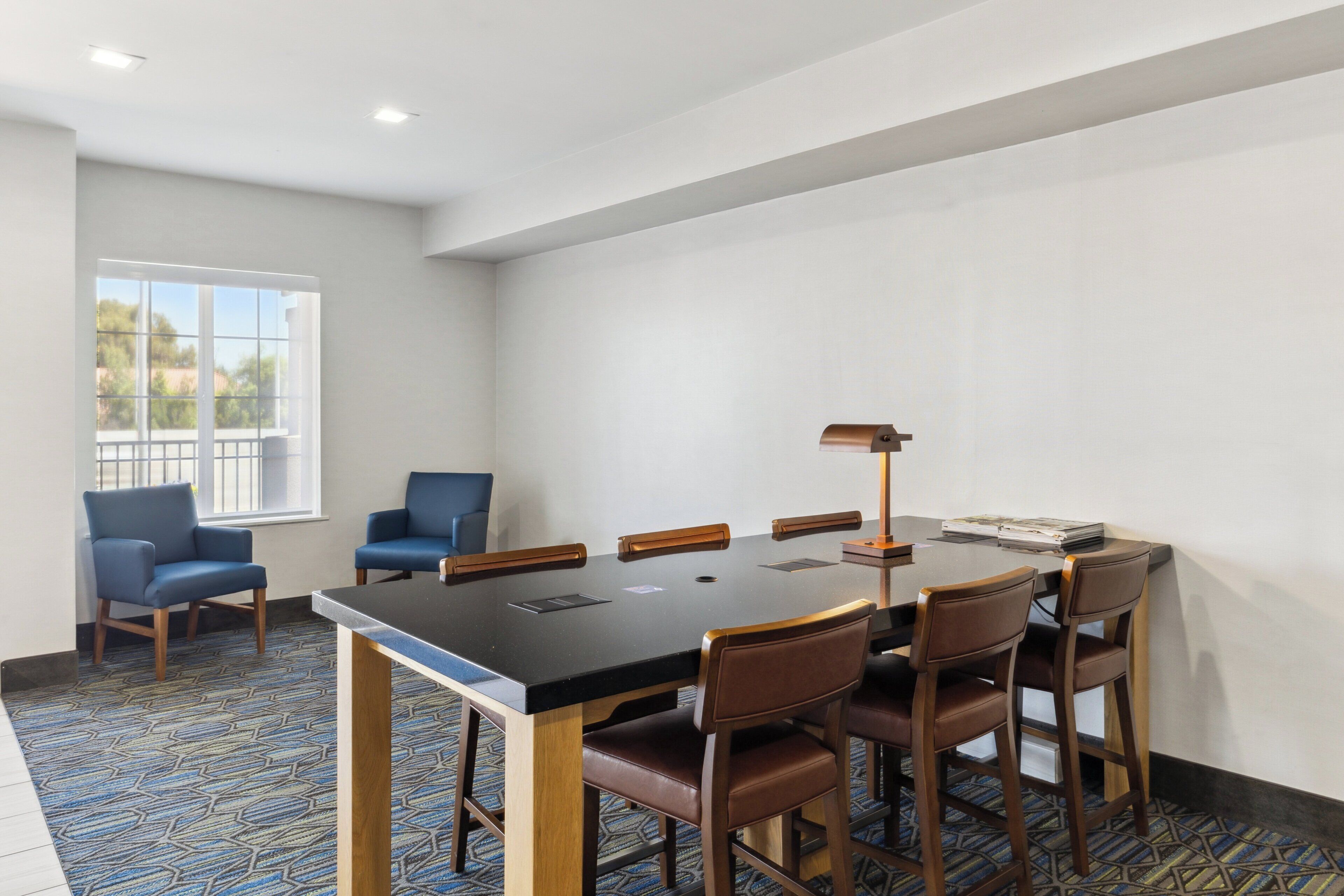 A conference room with a large table, six chairs, and a lamp.
