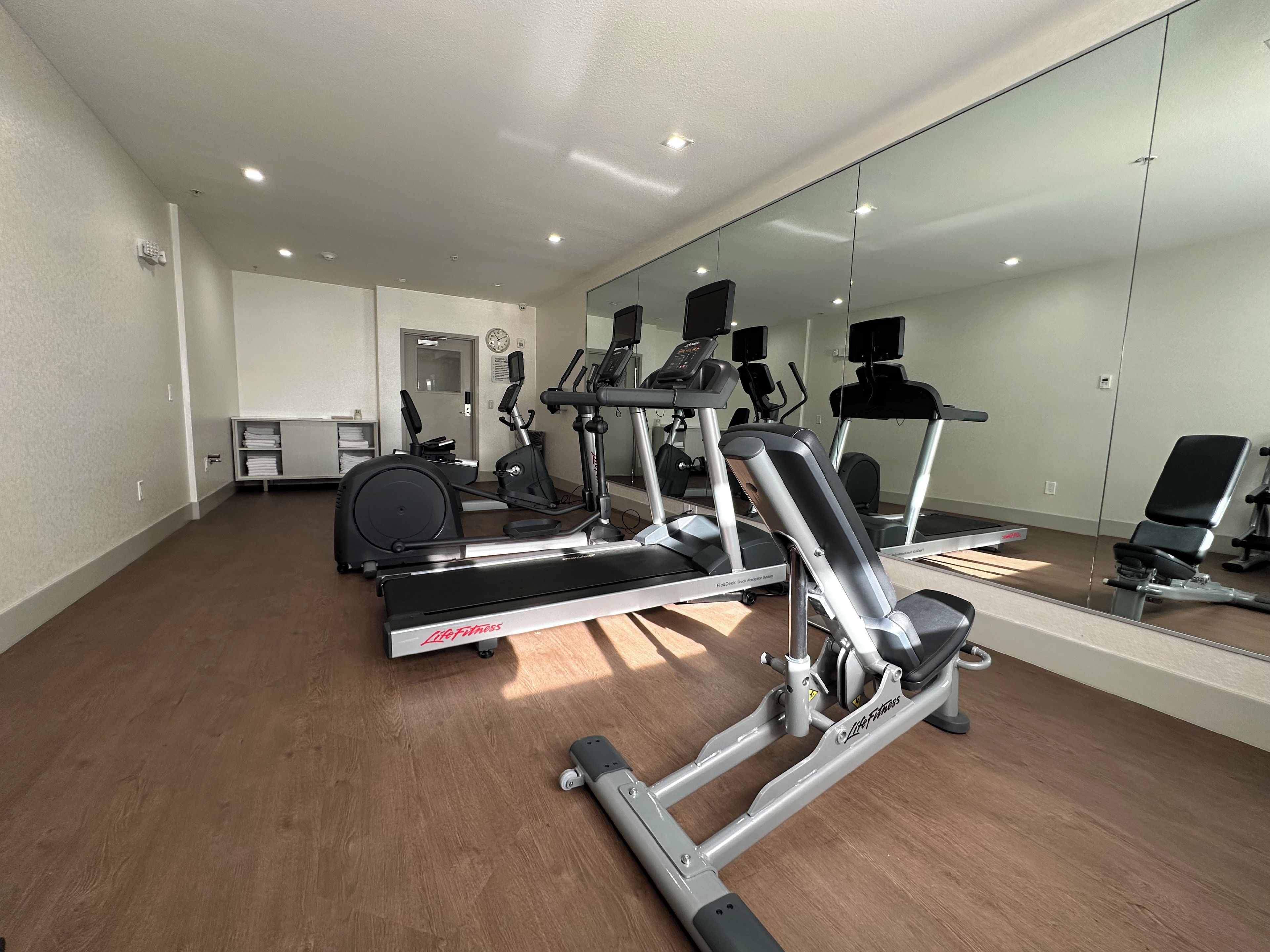 Ett gym med konditionsmaskiner, utrustning för styrketräning och en vägg med speglar.