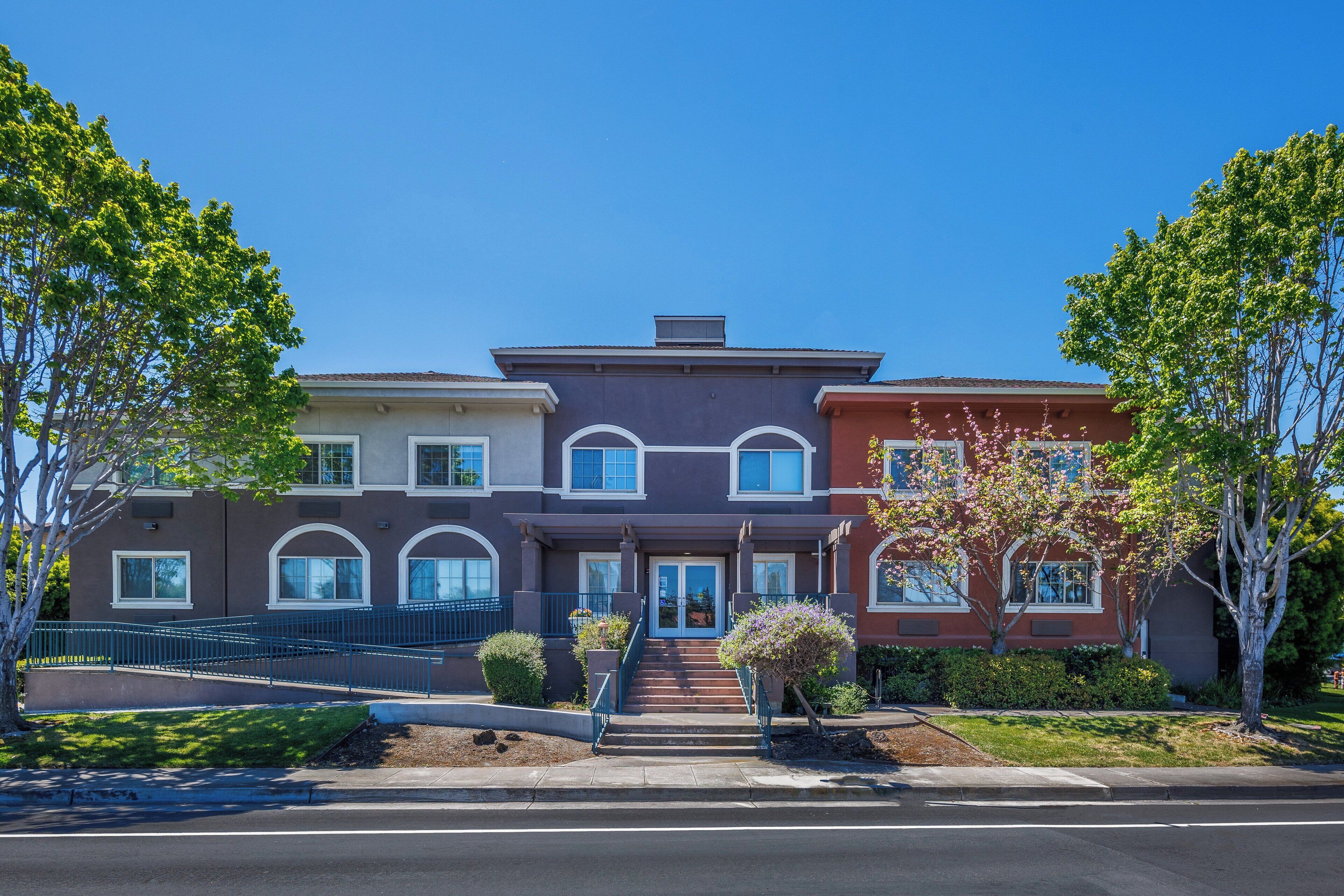 A multi-story residential building with a central entrance, a staircase, and a small front garden.