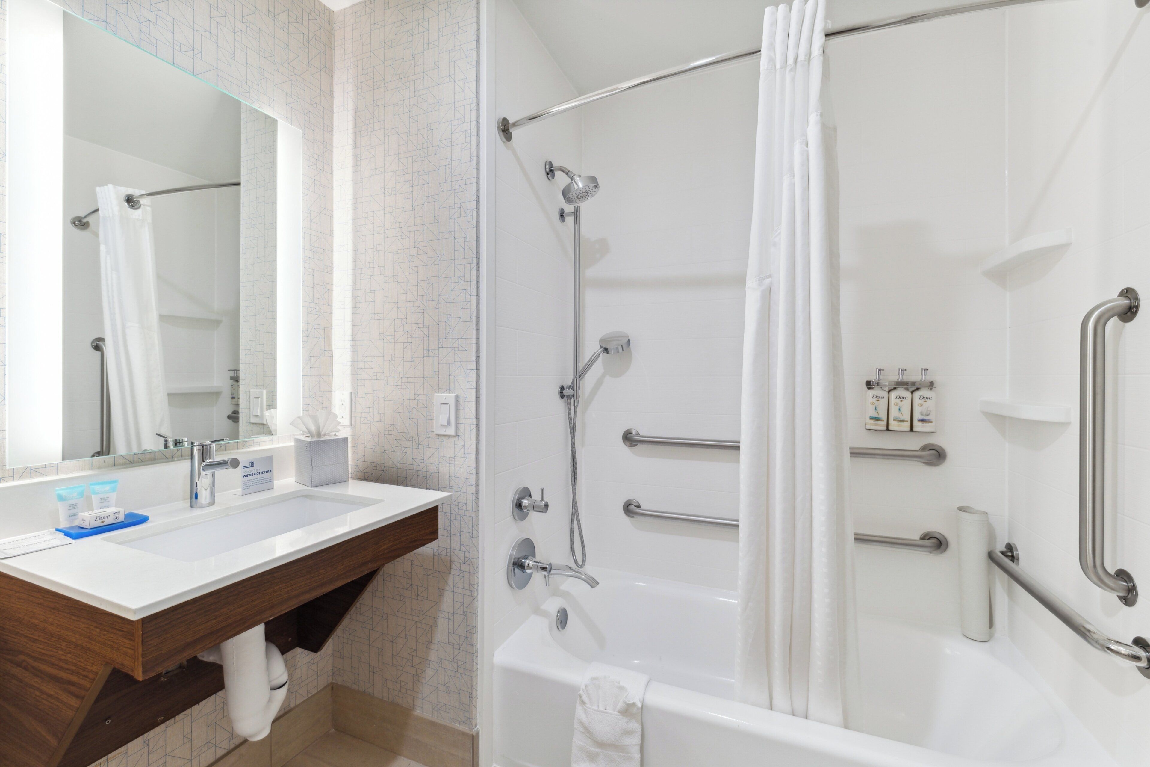 Un baño con lavamanos blanco, espejo y ducha.