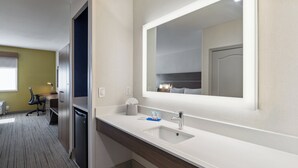 Un baño de hotel moderno con un espejo grande, un lavabo y un inodoro.