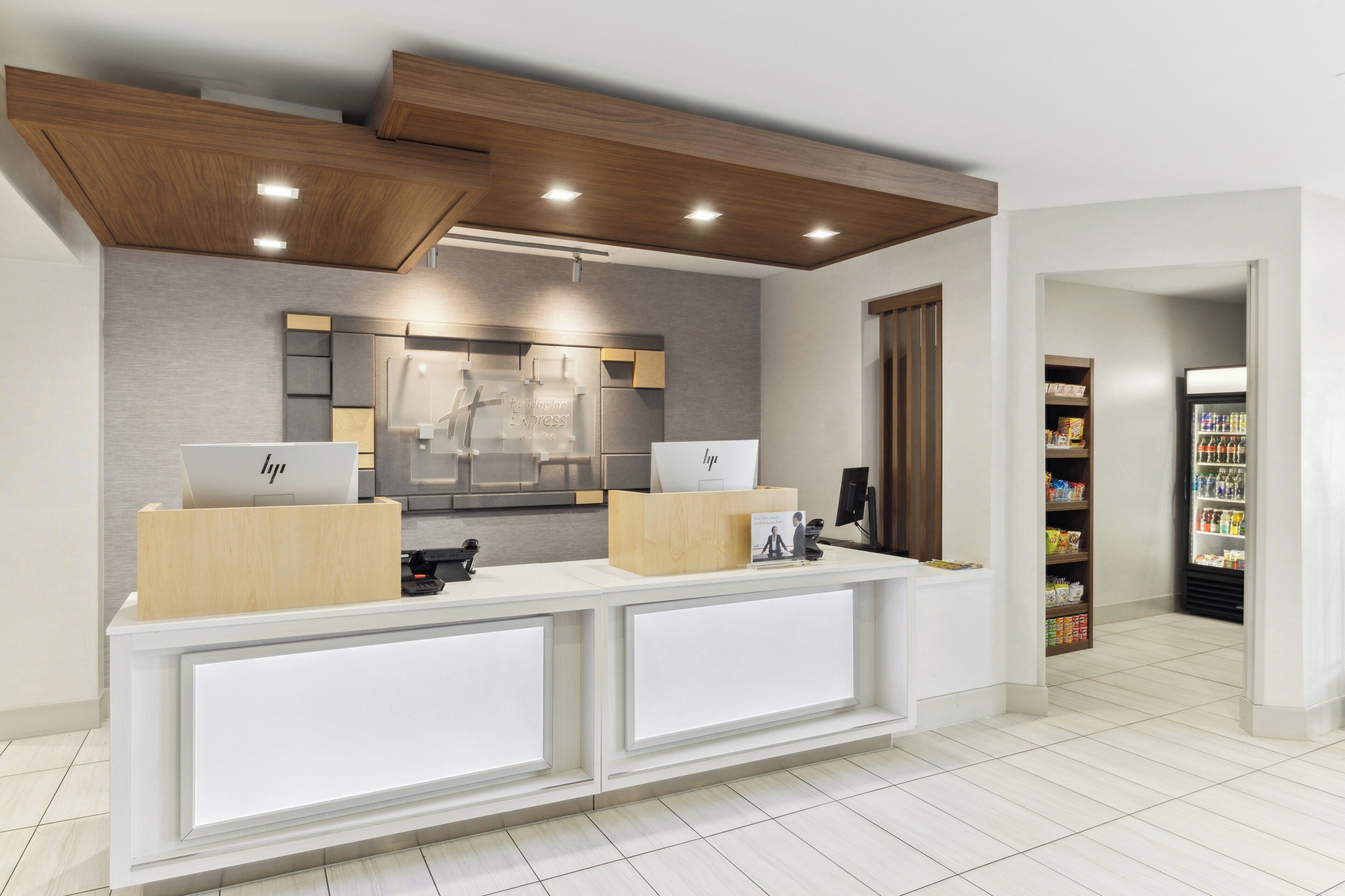 A reception area with a modern design, featuring a reception desk, a mirror, and a wall-mounted display.