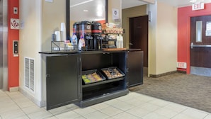 Un espace d’accueil d’hôtel comprenant un coin café, une poubelle et un panneau indiquant la sortie.