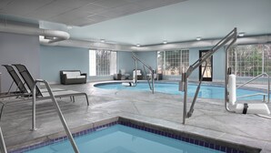 An indoor swimming pool with clear blue water, surrounded by lounge chairs and a sofa. - Holiday Inn Express Spokane Airport by IHG (Spokane)