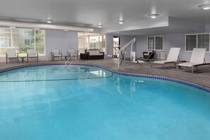 An indoor swimming pool with clear blue water, surrounded by white lounge chairs and a sofa. - Holiday Inn Express Spokane Airport by IHG (Spokane)