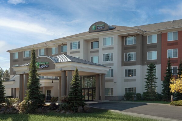 A Holiday Inn Express building with a covered entrance, multiple windows, and a landscaped front yard with trees. - Holiday Inn Express Spokane Airport by IHG (Spokane)
