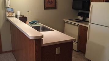 A kitchen with wooden cabinets, a white refrigerator, a stove, and a sink.