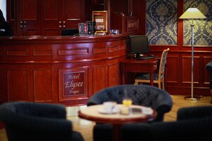 Un'area reception di un hotel con una scrivania in legno, un computer e una sedia.