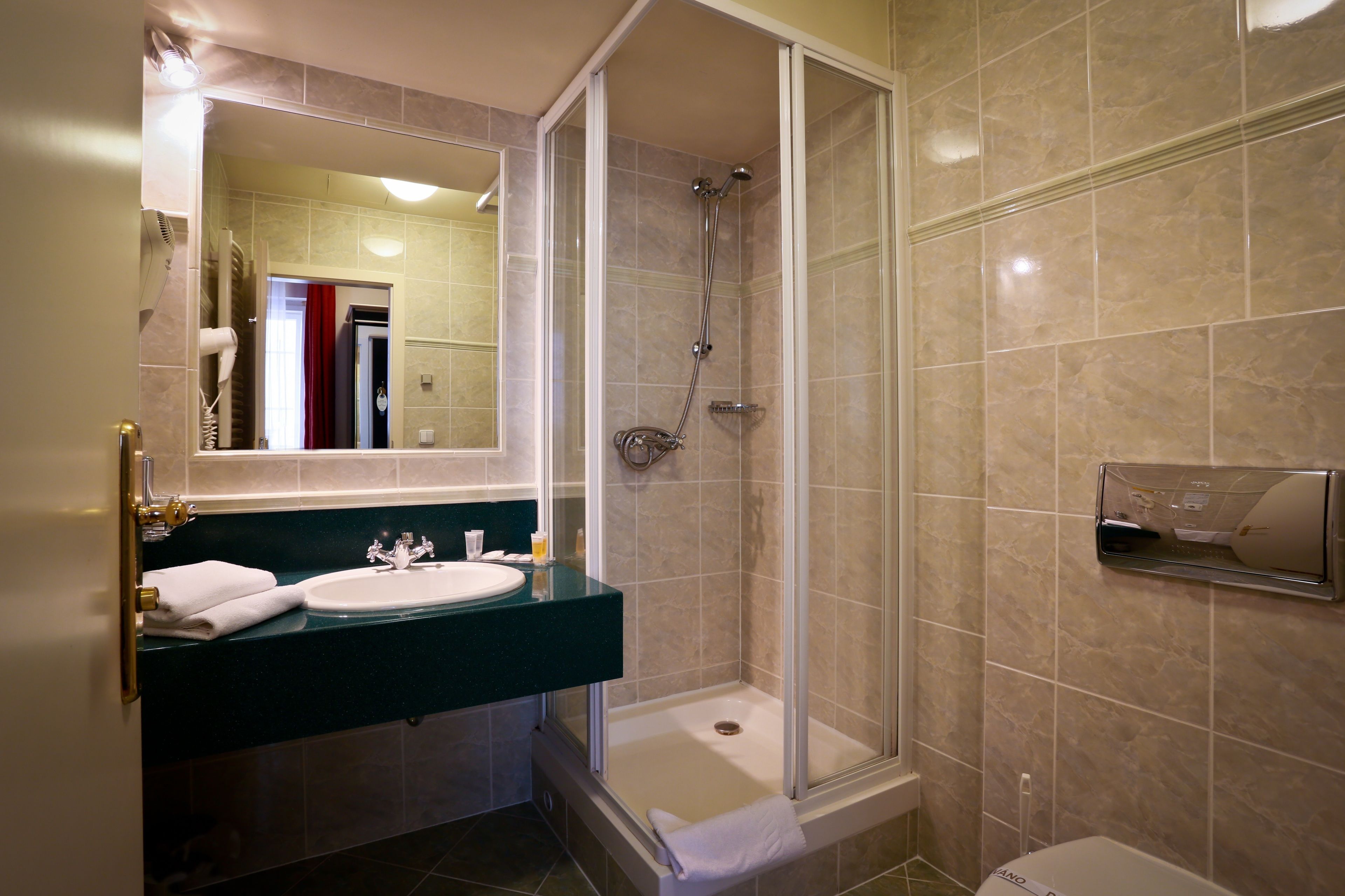 A bathroom with a sink, mirror, shower, and toilet.