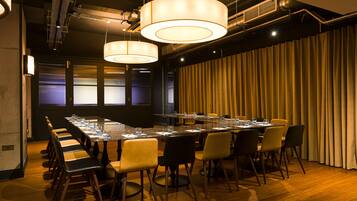 A conference room with a long table, chairs, and hanging lights.