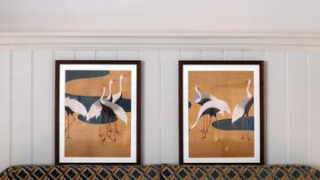 Two framed artworks of birds on a wall above a patterned sofa.