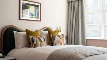 A neatly made bed with a variety of pillows, a bedside lamp, and a framed picture on the wall.