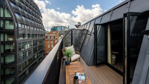 A modern balcony with a wooden floor, a potted plant, and a magazine. - The Chamberlain Hotel (London)