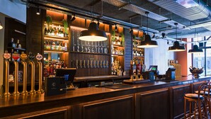 A bar area with a wooden counter, multiple taps, and a variety of bottles and glasses. - The Chamberlain Hotel (London)