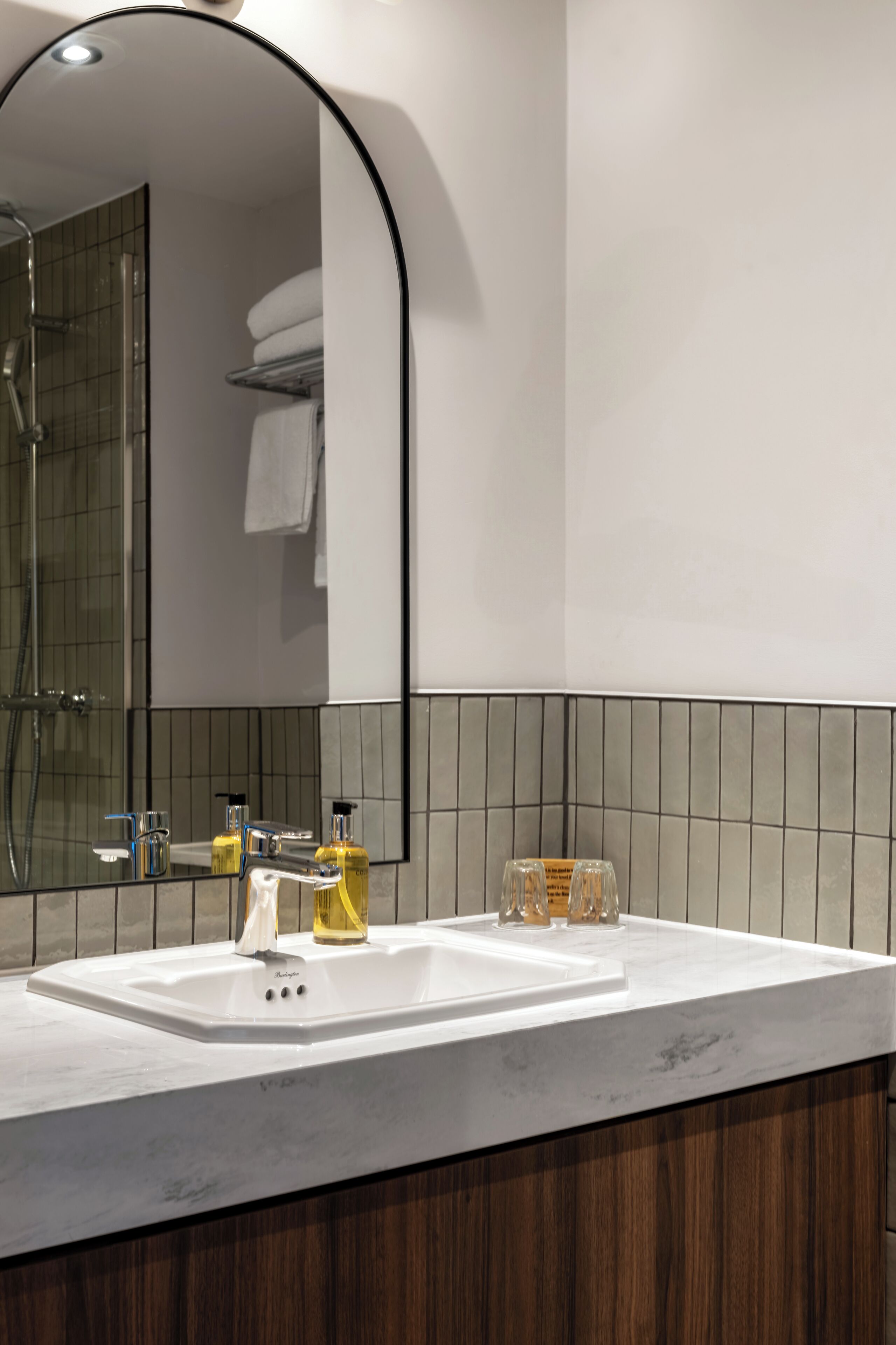 A bathroom with a white sink, a mirror, and a shower.