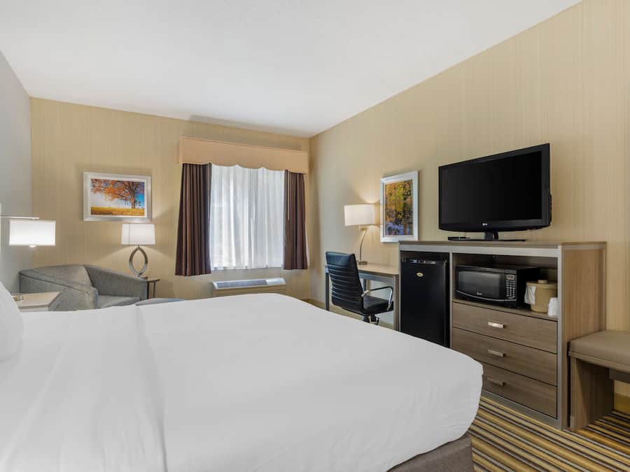 Une chambre d’hôtel avec un grand lit, un bureau avec un ordinateur, une télévision, un four à micro-ondes et un coin salon.