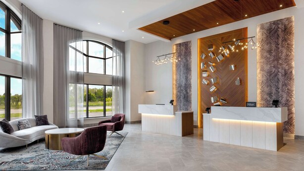 A modern hotel lobby with a reception desk, seating area, and large windows offering a view of the outdoors. - DoubleTree by Hilton Kingston (Kingston)