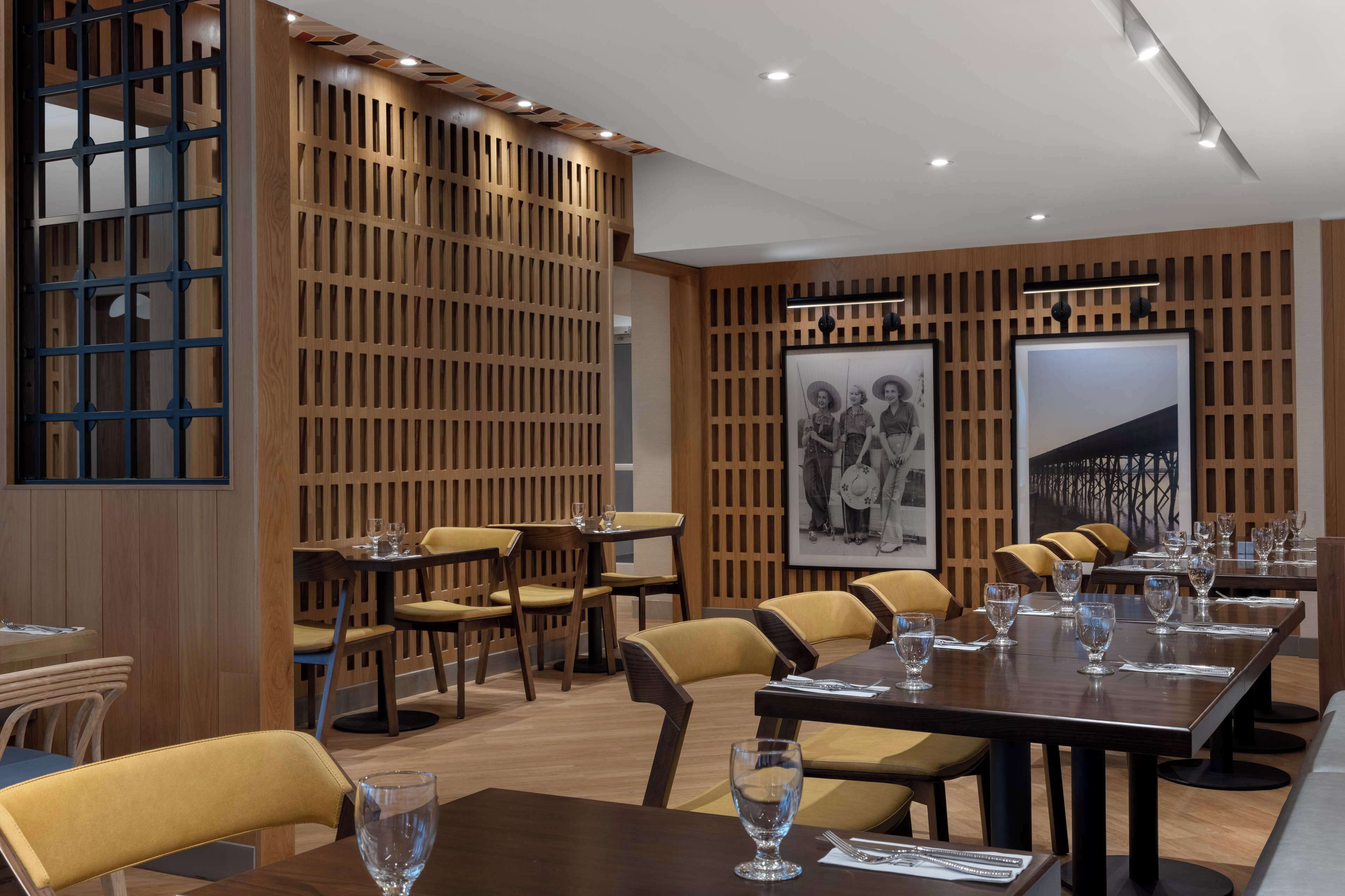 A modern dining area with wooden paneling, yellow chairs, and tables set for dining.