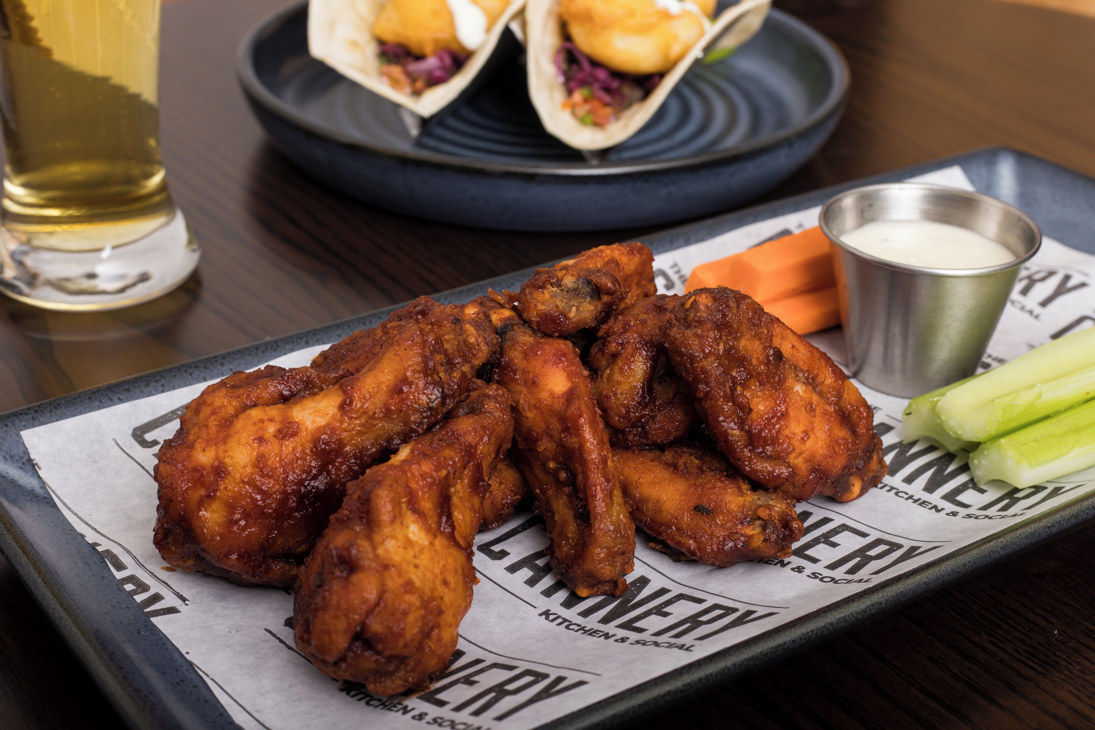 A tray with fried chicken wings, celery sticks, and a dipping sauce.