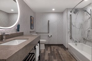 A modern bathroom with a large mirror, two sinks, a toilet, and a walk-in shower. - DoubleTree by Hilton Kingston (Kingston)