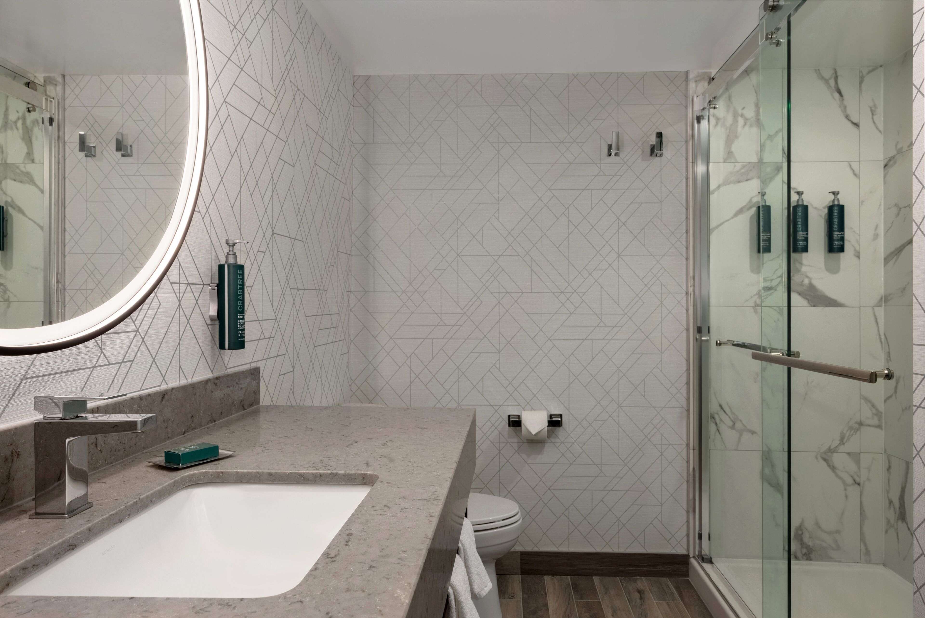 Une salle de bain moderne avec un grand miroir, un lavabo, des toilettes et une douche à parois de verre.
