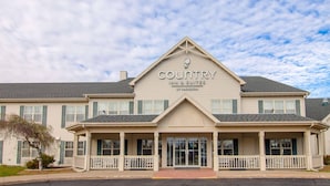 Edificio de Country Inn & Suites con fachada simétrica, ventanas grandes y una entrada destacada con porche cubierto.