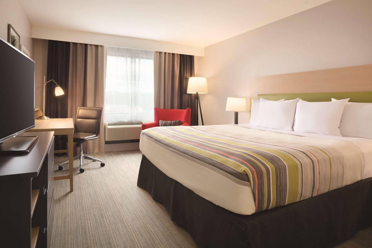A hotel room with a bed, desk, chair, and lamps.