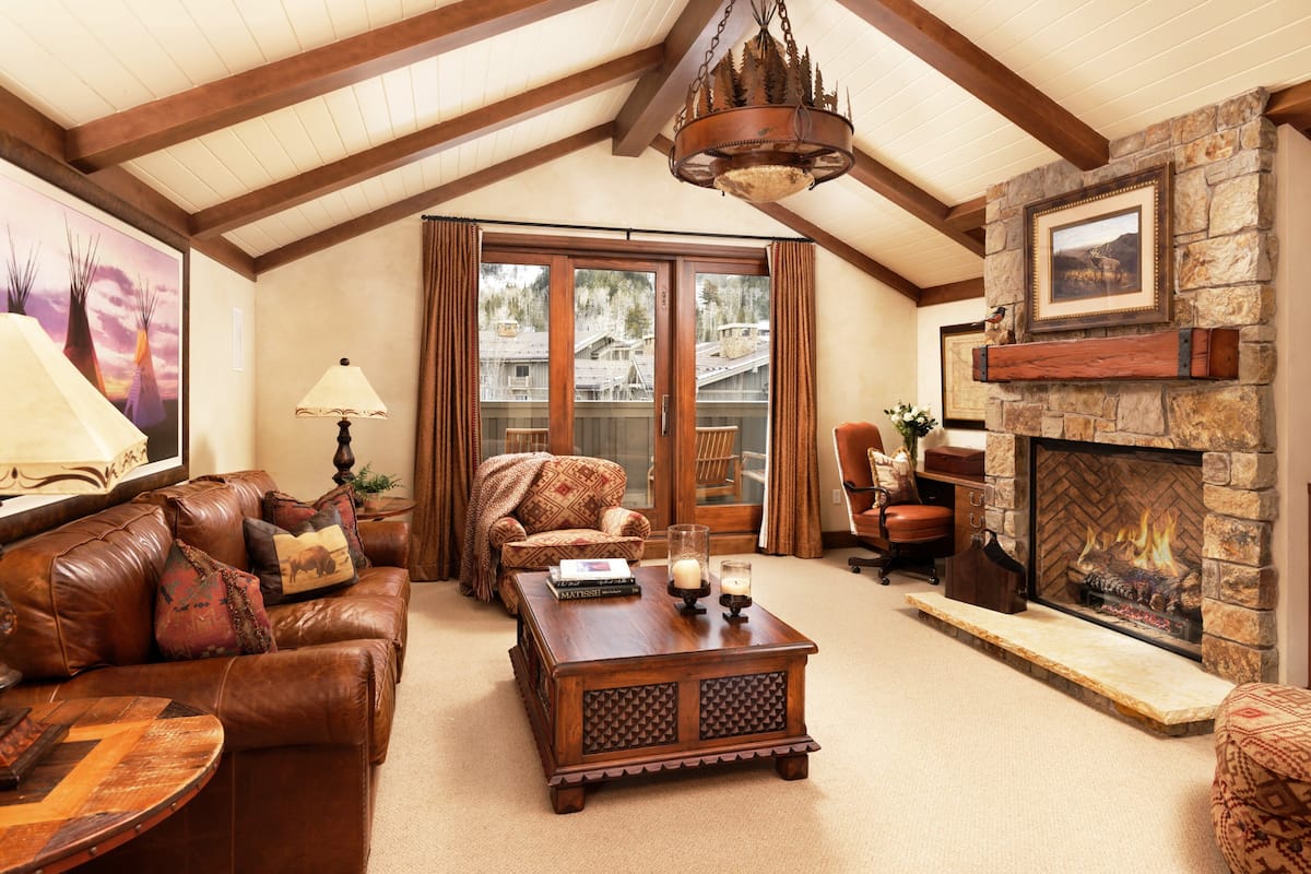A cozy living room with a leather sofa, a wooden coffee table, and a stone fireplace.
